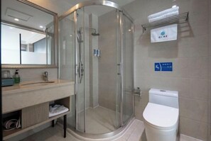 Une salle de bain moderne avec une douche à parois de verre, des toilettes blanches et un lavabo avec un miroir au-dessus.