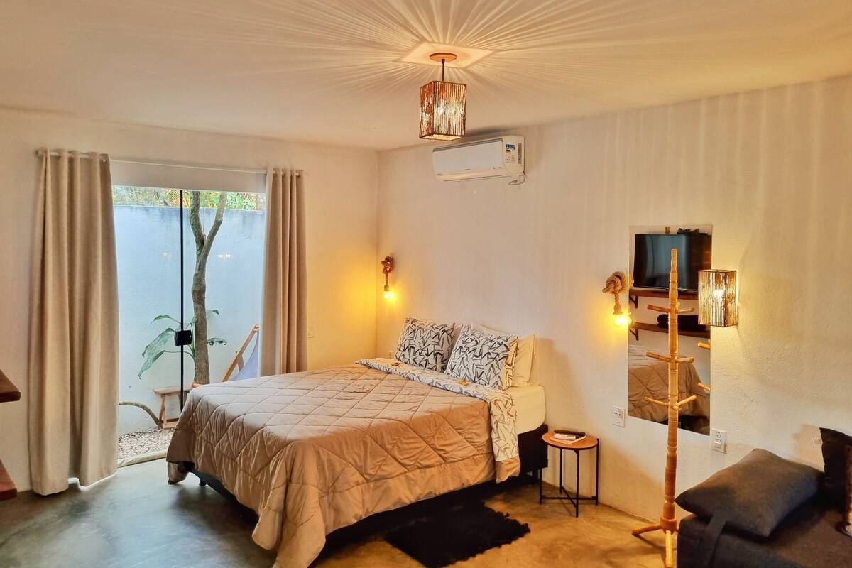 Ein Schlafzimmer mit einem Bett, einem kleinen Tisch, einem Stuhl, einem Fernseher und einer Klimaanlage.