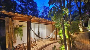 A hammock under a wooden pergola, a small covered seating area, and a pathway leading to a building. - Morada dos Saguis Chalés (Alto Paraíso de Goiás)
