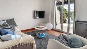 A modern living room with a sofa, a coffee table, and a TV mounted on the wall. - In estate with swimming pool, tennis, club house, house for 6 people, sea view (SAINTE MAXIME)