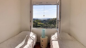 A small room with two beds, a window with a view of a landscape, and a small table with a lamp. - In estate with swimming pool, tennis, club house, house for 6 people, sea view (SAINTE MAXIME)