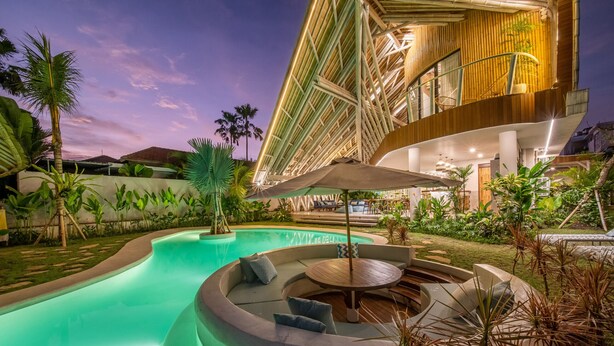 Un área de piscina exterior moderna con un diseño de asientos curvo y una terraza de madera.