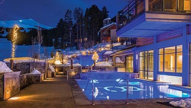 A modern building with a pool area, surrounded by snow-covered terrain and trees. - SPRING BREAK - SLOPESIDE Luxury Ski-in/Ski-out- Grand Colorado Peak 8 - SLEEPS 4 (Breckenridge)