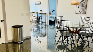 A modern dining area with a glass table and chairs, a trash bin, and pendant lighting. - Modern Luxury! Central Downtown Condo with parking! (License #6072) (Estes Park)