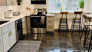 A modern kitchen with stainless steel appliances, a large window, and bar stools. - Modern Luxury! Central Downtown Condo with parking! (License #6072) (Estes Park)