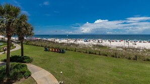 A beach with rows of beach chairs and umbrellas, a clear sky, and a view of the ocean. - Fall discounts! Unobstructed beach & pool views from corner wraparound balcony (Orange Beach)