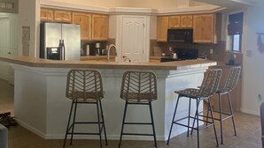 A spacious kitchen with a central island, wooden cabinets, and a built-in microwave.
