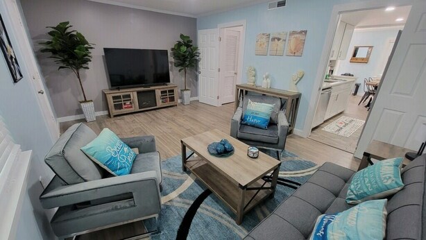 Una sala de estar moderna con un sofá gris, una mesa de centro de madera y una televisión.