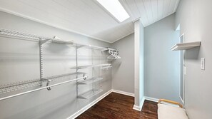 A walk-in closet with metal shelving units, a hanging rod, and a bench.