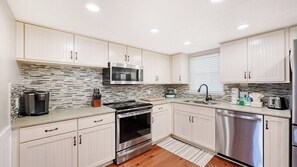 A modern kitchen with white cabinets, a stainless steel microwave, a built-in oven, and a dishwasher.