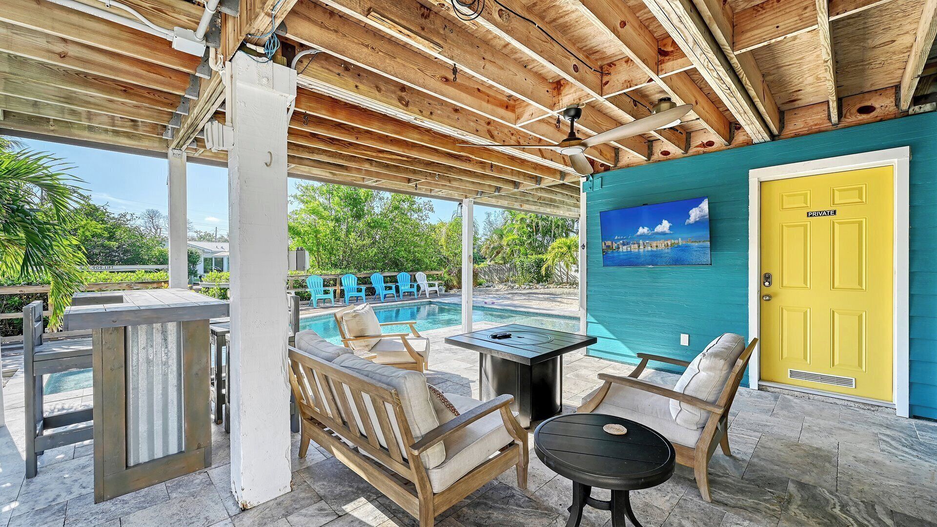 A covered outdoor area with a pool, lounge chairs, and a table.