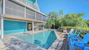 A poolside area with a pool, blue chairs, and a covered seating area.
