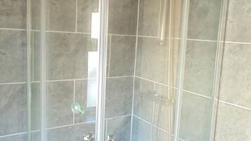 A glass-enclosed shower with a curved ceiling, tiled walls, and a visible showerhead.
