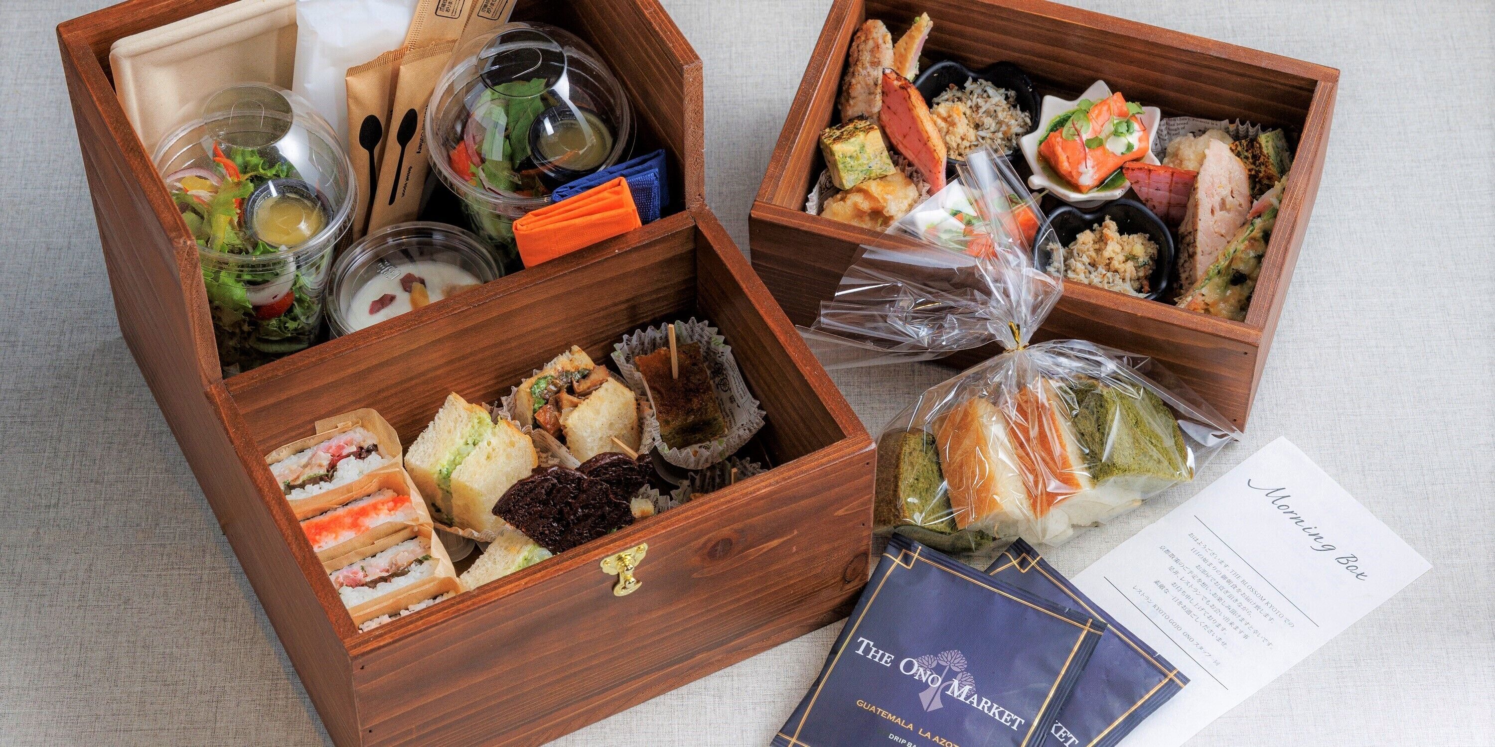Dos cajas de madera con diversos alimentos y una tarjeta de presentación.