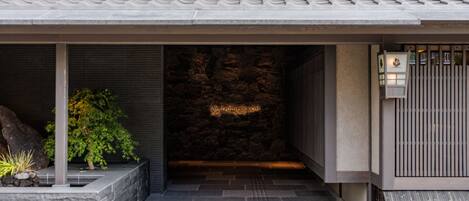 A modern entrance with a stone wall, a potted plant, and a metal gate.