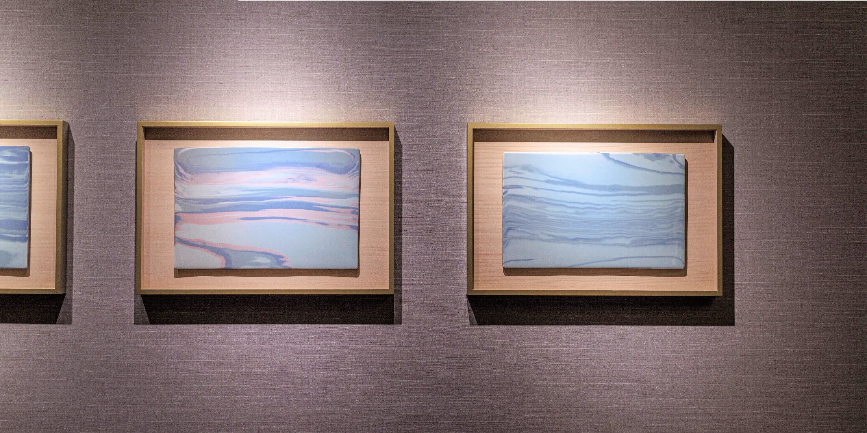 Three framed artworks on a textured wall.