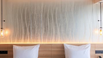 A modern hotel room with a wooden headboard, two white pillows, and a textured wall with vertical lines.