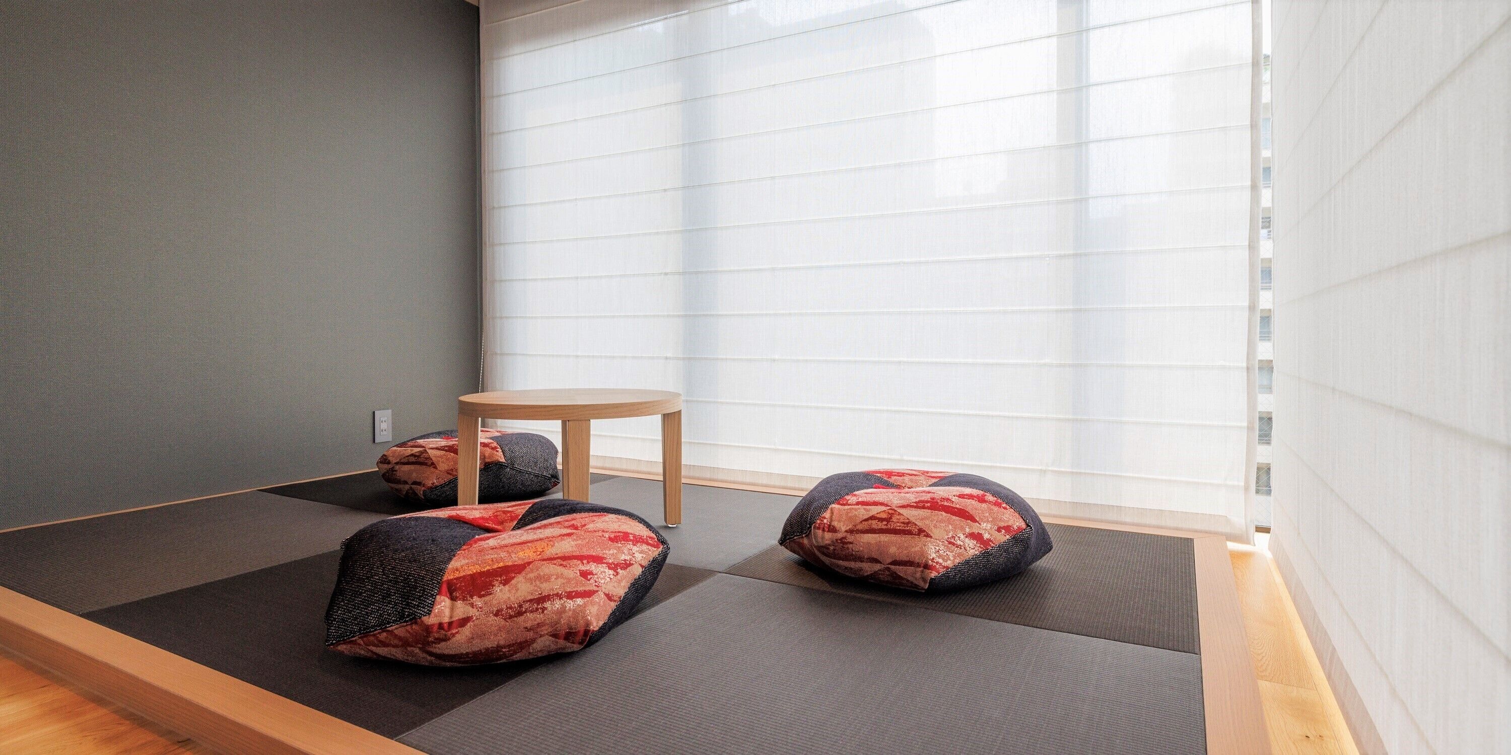 Una habitación con esteras de tatami, una pequeña mesa de madera y cojines.