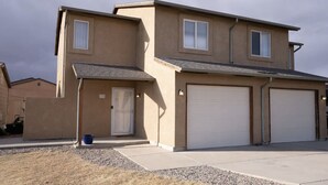 Une maison à deux étages avec un garage, une porte d’entrée et un petit porche.