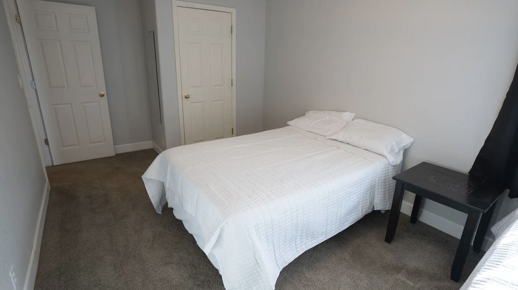 Een slaapkamer met een bed, een stoel en twee deuren.