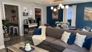 Un salon moderne comprenant un canapé d’angle, une table basse et un coin repas avec une table et des chaises.