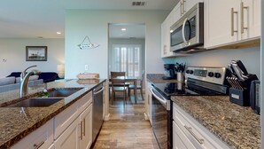 A modern kitchen with granite countertops, stainless steel appliances, and white cabinetry. - 1st Floor, Pets Friendly, Shared Pool Hot Tub, Near Marina (Port Aransas)