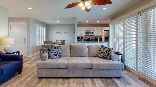 A spacious living room with a beige sofa, a blue armchair, and a ceiling fan. - 1st Floor, Pets Friendly, Shared Pool Hot Tub, Near Marina (Port Aransas)