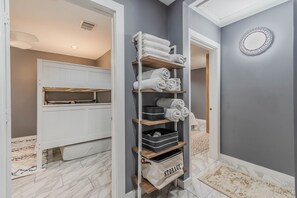 Storage space with shelving unit, towels, and bins for organized essentials.