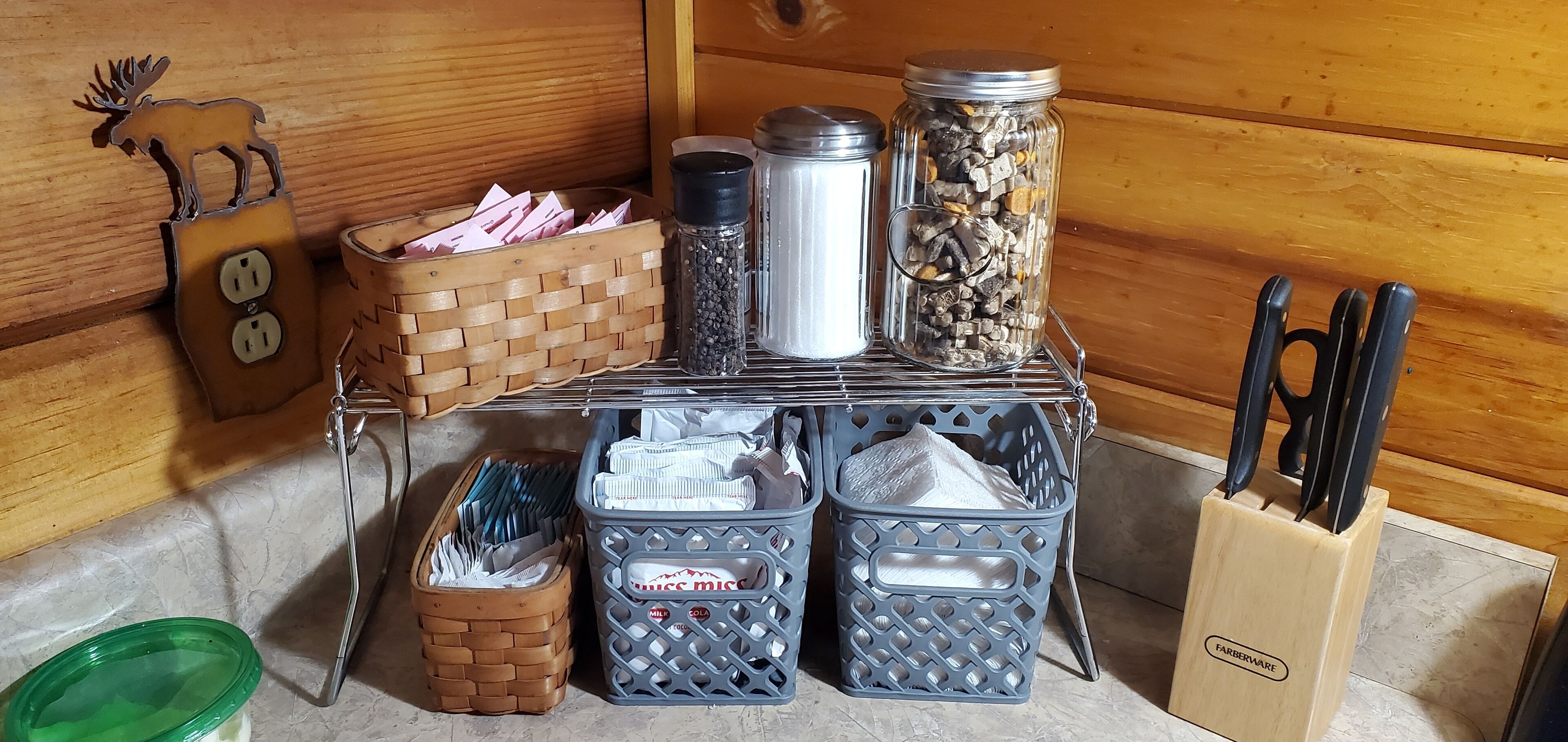 Una encimera de cocina con varios recipientes de almacenamiento, un bloque de cuchillos y un adorno.