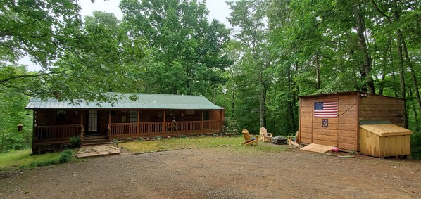 A cabin with a porch and a small shed with an American flag. - GUNSMOKE The not so "tiny"  cabin with fenced back yard! (Ellijay)