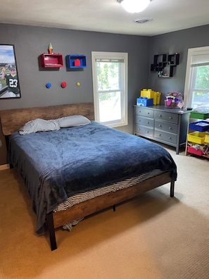 Un dormitorio con una cama grande, un aparador y una ventana.