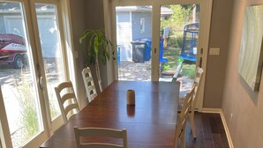 Ein Esszimmer mit einem großen Holztisch, weißen Stühlen und einem Deckenventilator.