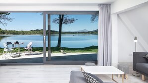 A modern living room with a large sliding glass door leading to a lakeside view. - Stunning Waterfront Lodge (Stirling)