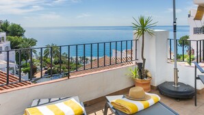Ein Balkon mit zwei Liegestühlen, einem Blumentopf und Blick aufs Meer.