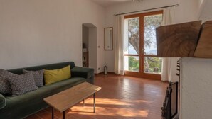 A living room with a green sofa, a wooden coffee table, and a large window with curtains.