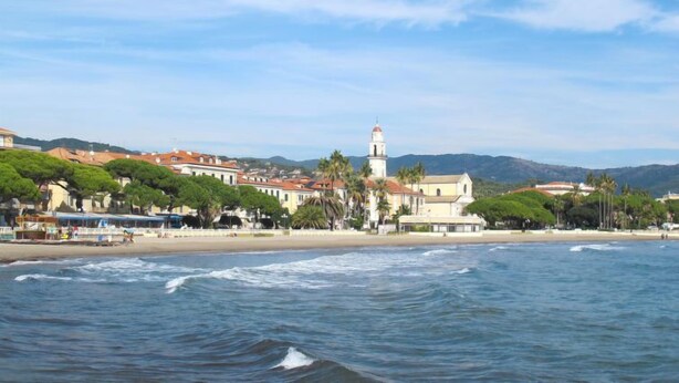 A coastal town with a prominent lighthouse, beach, and residential buildings.