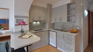 A compact kitchen with a white countertop, a sink, a microwave, and a dish rack. - Charming studio for rent in Roses, Costa Brava! Sleeps 3, modern amenities, pool, free Wi-Fi, close to beach. (Roses)