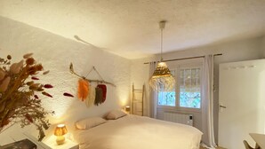 Un dormitorio con cama, mesita de noche, lámpara y ventana con cortinas.