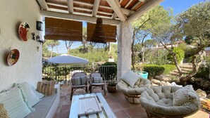 Un patio al aire libre con mobiliario de mimbre, una mesa y una pérgola.