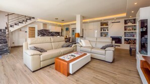 Uma sala de estar moderna com dois sofás bege, uma mesa de centro de madeira e uma escadaria.
