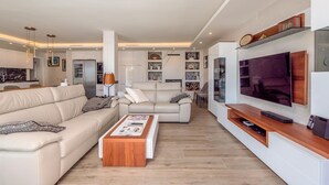 Uma sala de estar moderna com sofá, mesa de centro, TV e estantes embutidas.