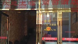 Ein Hotel Eingang mit Glastüren und einem Schild, das ein besonderes Angebot für ein Zimmer mit 1,5 Metern Länge anzeigt.