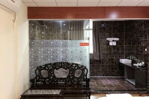Un baño con ducha, lavabo, espejo y banco.