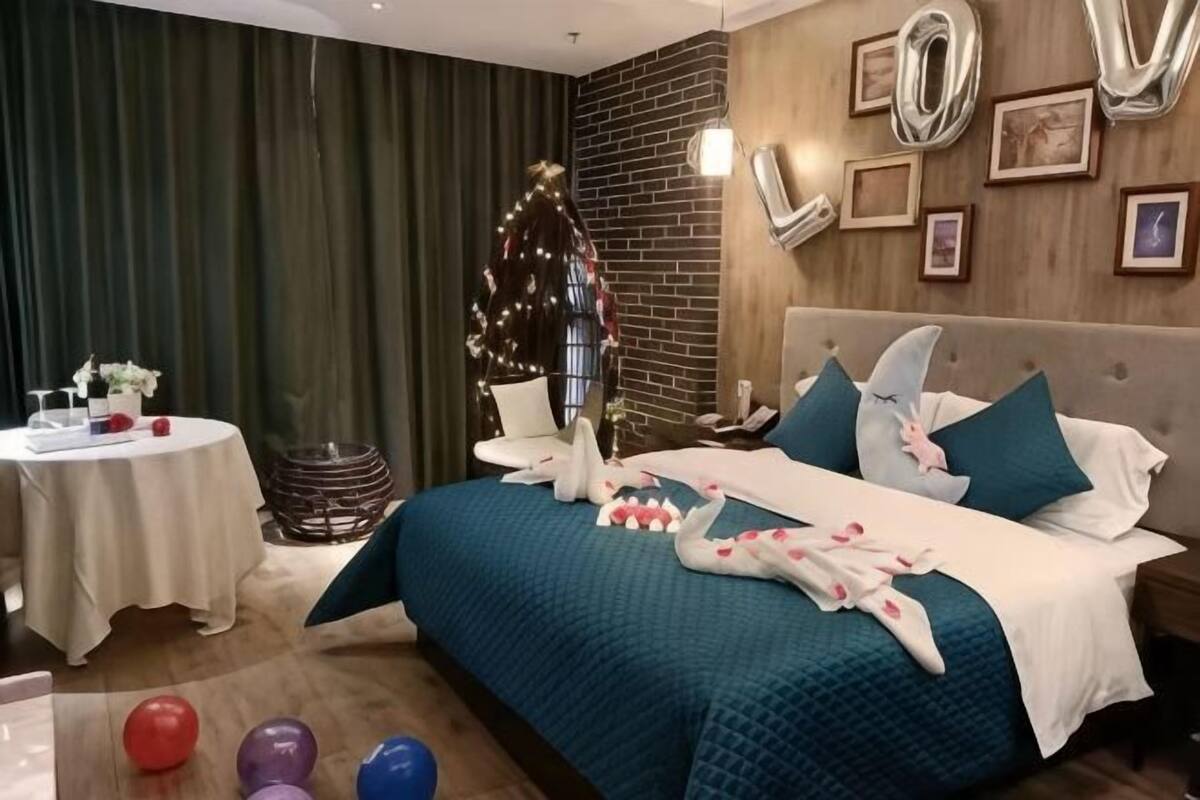 Um quarto com uma cama, uma mesa redonda e um pinheiro de Natal.