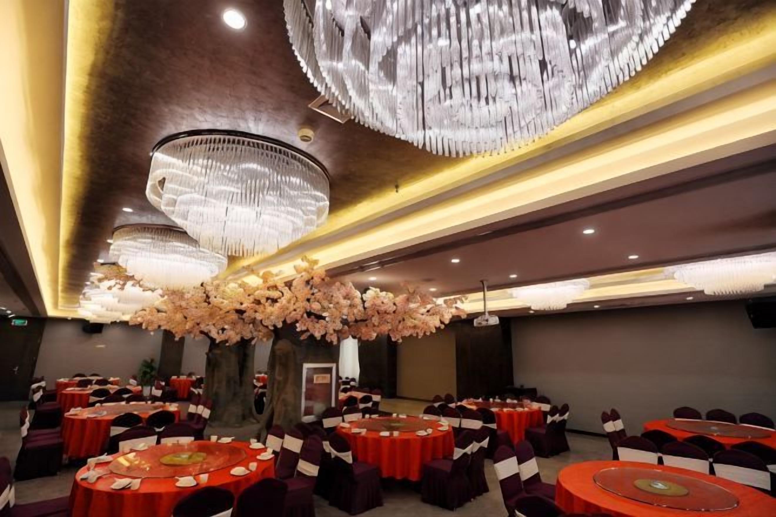 Un salón de banquetes con mesas redondas, candelabros y un centro de mesa floral.