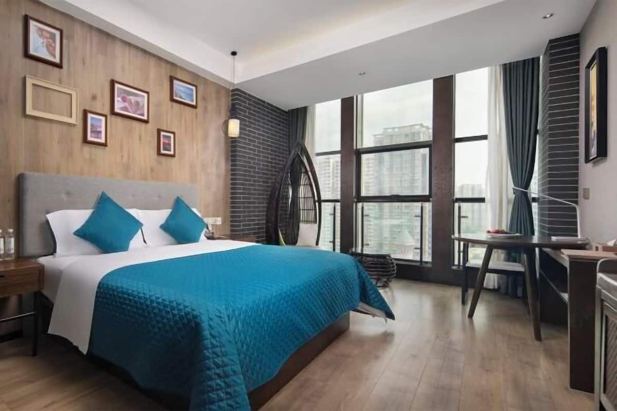 A modern hotel room with a large bed, a desk, and a view of the city.