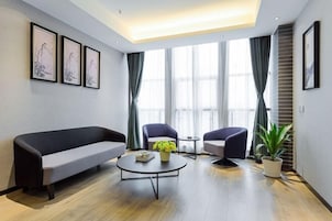 Una sala de estar moderna con un sofá, dos sillones, una mesa de centro y una planta en maceta.