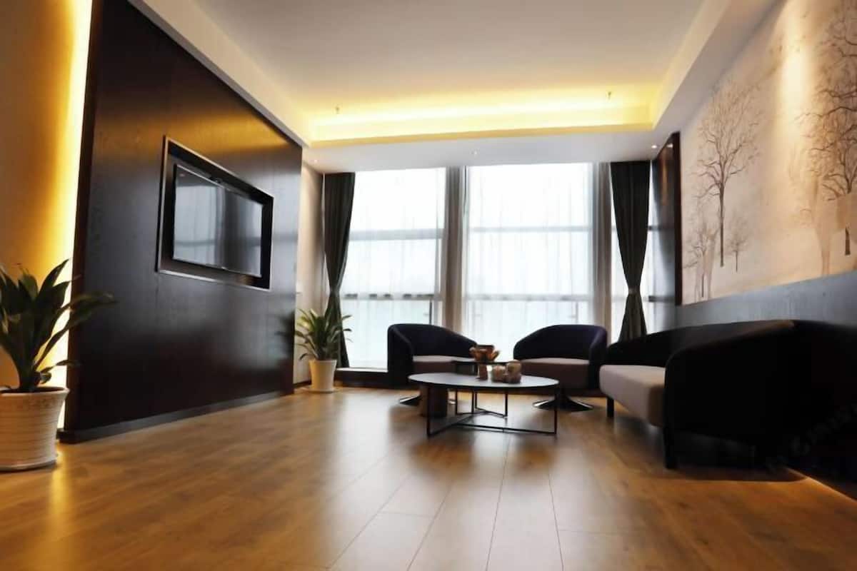 A modern living room with a sofa, two armchairs, a coffee table, and a TV mounted on the wall.