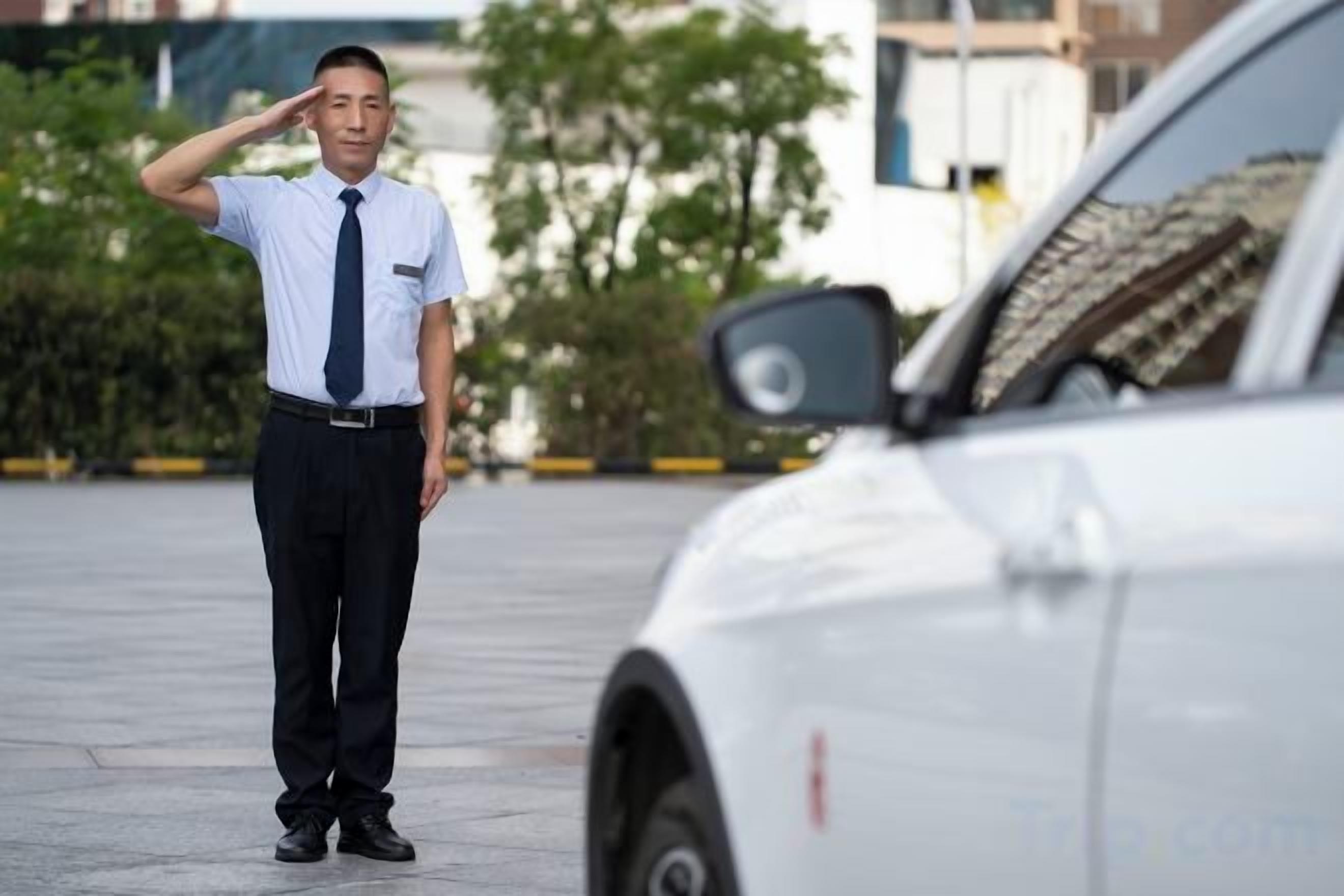 A person standing next to a white car in an outdoor setting.