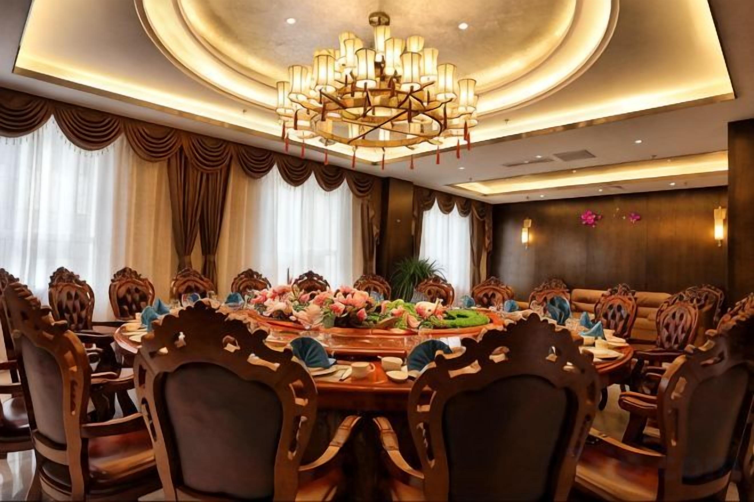 A formal dining room with a large round table, ornate chairs, and a chandelier.